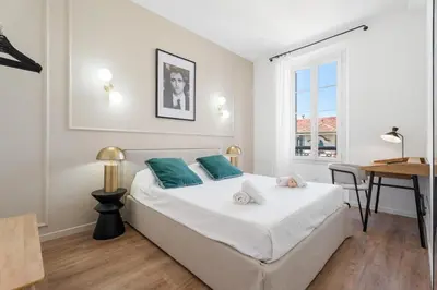 a bedroom with a large white bed with blue pillows at Appartement Caire - Welkeys in Cannes