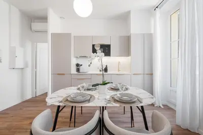 a white dining room with a table and chairs at Appartement Caire - Welkeys in Cannes
