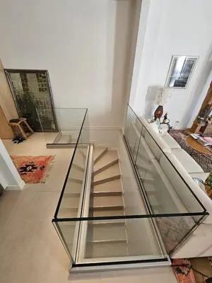a glass staircase in a house with a woman sitting on a couch at 3 bedroom house in the center of Cannes in Cannes
