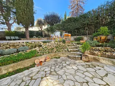 a garden with a stone patio with benches and trees at 3 bedroom house in the center of Cannes in Cannes