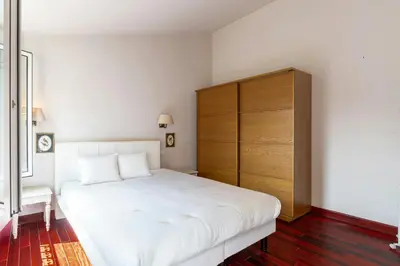 a bedroom with a white bed and a wooden cabinet at Cannes Centre Le bourbon 1min mer et Croisette in Cannes