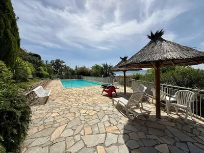 a patio with chairs and an umbrella and a pool at B084-Confort et serenite piscine et stationnement in Cannes