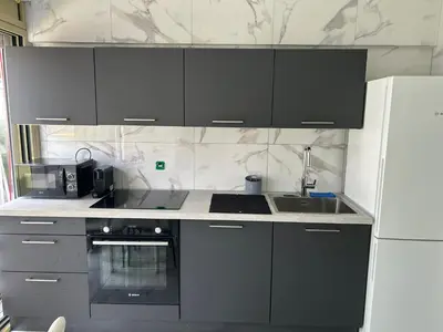 a kitchen with black cabinets and a white refrigerator at Cannes Croisette in Cannes