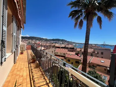 a balcony with a palm tree and a city at Belle-epoque apartment ,3bedrooms with sea view in Cannes