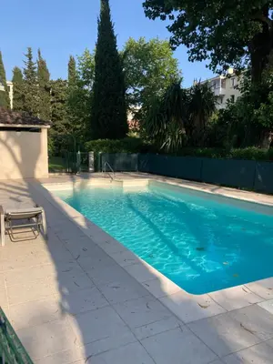 a swimming pool with blue water in a yard at Studio neuf parking piscine à Cannes in Cannes