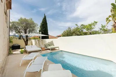 a swimming pool with white chairs and a white wall at Immogroom - Luxury Villa with Swimming Pool in City Center in Cannes