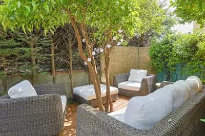 a patio with wicker chairs and chairs and a tree at Immogroom - Luxury Villa with Swimming Pool in City Center in Cannes