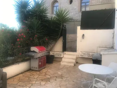 a patio with a grill and a table and palm trees at villa matama in Cannes