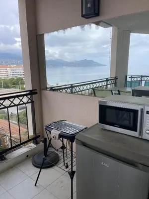 a kitchen with a microwave on a counter with a balcony at Cannes Beach Residence vue mer et pisicne in Cannes