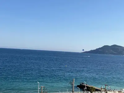 a large body of water with a beach and mountains at Cannes Beach Residence vue mer et pisicne in Cannes