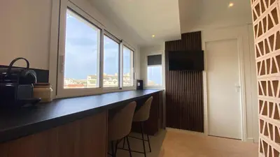 a kitchen with a bar with chairs and windows at Cannes Croisette in Cannes