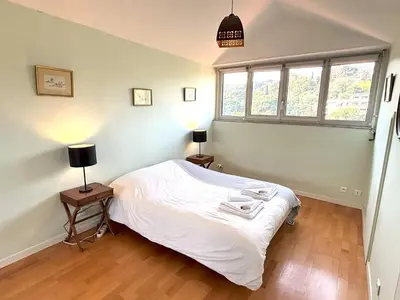 a bedroom with a bed and two lamps and a window at Appartement 3p vue mer proche plages et congrès in Cannes