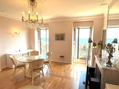 a dining room with a table and chairs and a chandelier at Appartement 3p vue mer proche plages et congrès in Cannes