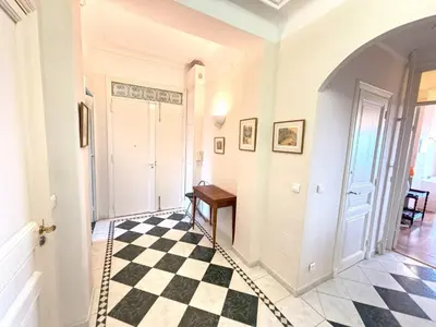 a hallway with a checkerboard floor and a door at Appartement 3p vue mer proche plages et congrès in Cannes