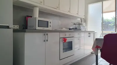 a kitchen with white cabinets and a table and a microwave at Studio Cannes Proche Palais des Festivals et Plages du Midi in Cannes