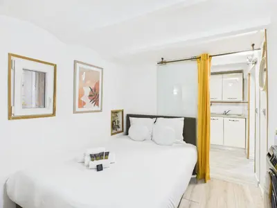 a white bedroom with a white bed and a window at LE MIMOSA mignon en plein centre-ville, emplacement parfait pour votre séjour in Cannes