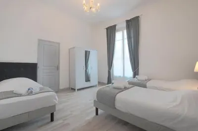 a bedroom with two beds and a mirror and a chandelier at Residence Michel Ange in Cannes