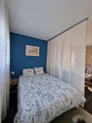 a bedroom with a bed with a blue wall at Bright apartment 10 minutes from Cannes in Le Cannet
