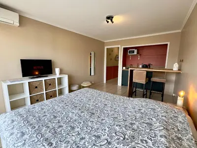 a bedroom with a large bed and a kitchen at Cannes Eden By SCLS Locations in Cannes