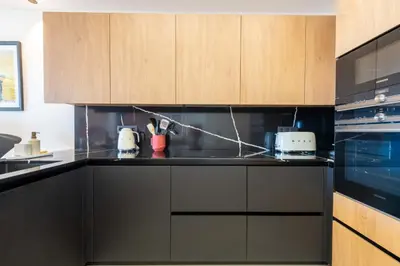 a kitchen with black counters and wooden cabinets at 2-Br Apartment with Sea View Terrace Cannes in Cannes