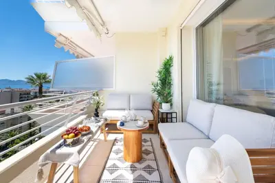 a living room with a couch and a tv on a balcony at 2-Br Apartment with Sea View Terrace Cannes in Cannes