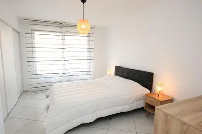 a white bedroom with a bed and a window at Paradisio in Cannes