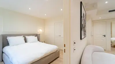 a bedroom with a white bed and a chair at 3BDR Cocoon in Cannes Martinez avec Jardin Privé & Design Contemporain à 5 min de la Croisette in Cannes