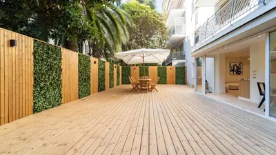 a wooden deck with a table and an umbrella at 3BDR Cocoon in Cannes Martinez avec Jardin Privé & Design Contemporain à 5 min de la Croisette in Cannes