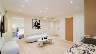 a large white room with a bed and a table at 3BDR Cocoon in Cannes Martinez avec Jardin Privé & Design Contemporain à 5 min de la Croisette in Cannes