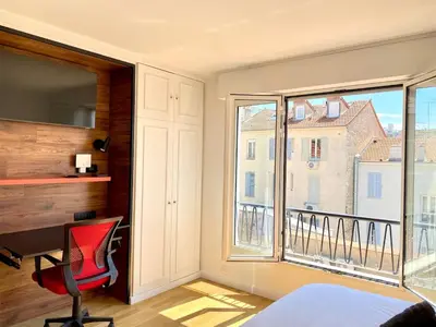 a bedroom with a red chair and a large window at Stylish Cannes Gem, Terrace, Parking, 100m to Croisette in Cannes