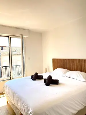 a large white bed with two brown towels on it at Stylish Cannes Gem, Terrace, Parking, 100m to Croisette in Cannes