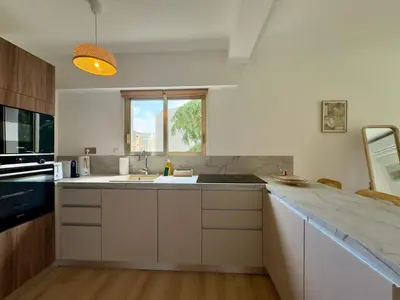 a white kitchen with a sink and a window at Le Cirodde By SCLS Locations in Cannes
