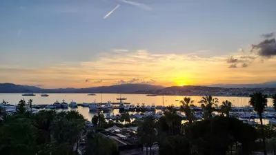 a sunset over a marina with boats in the water at Vue unique sur toute la baie de Cannes et la mer in Cannes
