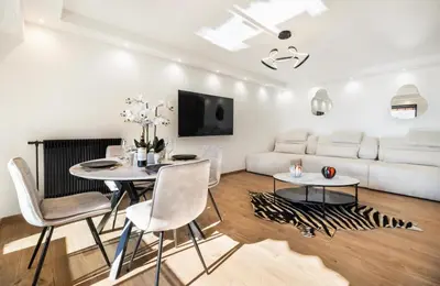 a living room with a white couch and a table and chairs at apartment in Cannes-Croisette in Cannes