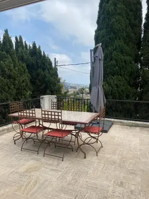 a table and chairs with an umbrella on a balcony at Bastide Anna in Le Cannet
