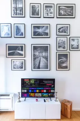 a living room with a tv and a wall with pictures at Le Corail - SCLS Locations in Cannes