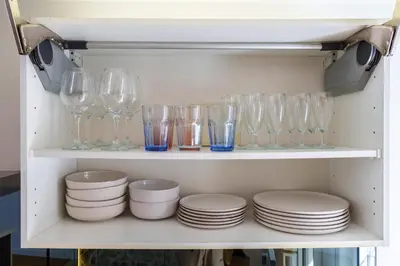 a shelf with wine glasses and plates on it at Le Corail - SCLS Locations in Cannes