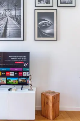 a living room with a tv and a table at Le Corail - SCLS Locations in Cannes