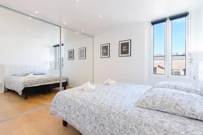 a white bedroom with two beds and a window at Le Corail - SCLS Locations in Cannes