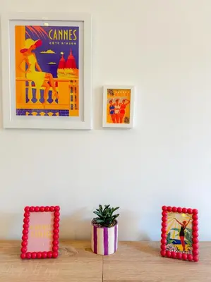two framed posters on a wall above a table with a plant at Le Rosy By ApiRent #Balcon #Wifi #Centre-ville in Cannes
