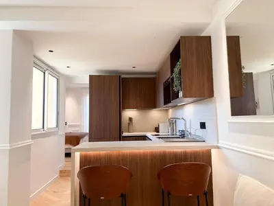 a kitchen with wooden cabinets and a counter with chairs at Appartement De Luxe 5 Mins à Pied Du Palais Des Festivals by Halldis in Cannes