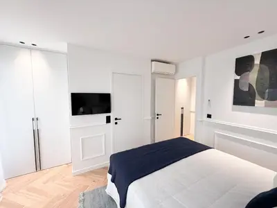 a white bedroom with a bed and a flat screen tv at Appartement De Luxe 5 Mins à Pied Du Palais Des Festivals by Halldis in Cannes