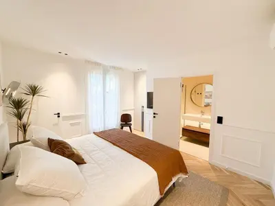 a white bedroom with a large bed and a bathroom at Appartement De Luxe 5 Mins à Pied Du Palais Des Festivals by Halldis in Cannes