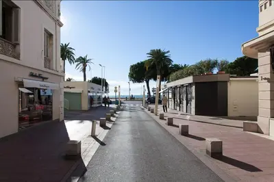 an empty street in a city with palm trees and buildings at CANNES - à 50m des plages et de la Croisette in Cannes