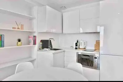 a white kitchen with white cabinets and a refrigerator at Beautiful 2-room apartment on the Croisette in Cannes in Cannes