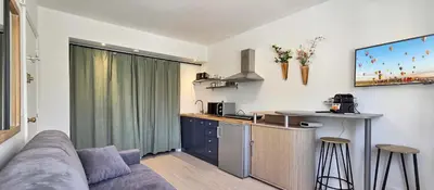 a living room with a couch and a kitchen at LX147 Studio lumineux centre, confort & autonomie in Cannes