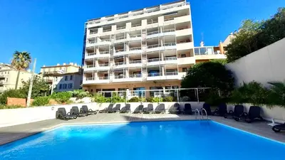 a hotel with a swimming pool in front of a building at Le Clémenceau - SCLS Locations in Cannes