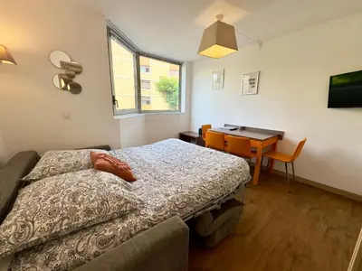 a bedroom with a bed and a table and a desk at Le Clémenceau - SCLS Locations in Cannes