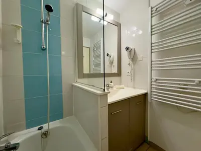 a bathroom with a tub and a sink and a mirror at Le Clémenceau - SCLS Locations in Cannes