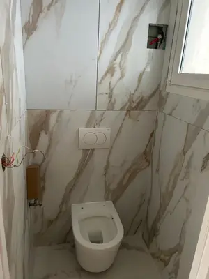 a bathroom with a white toilet and marble walls at Normandy in Cannes